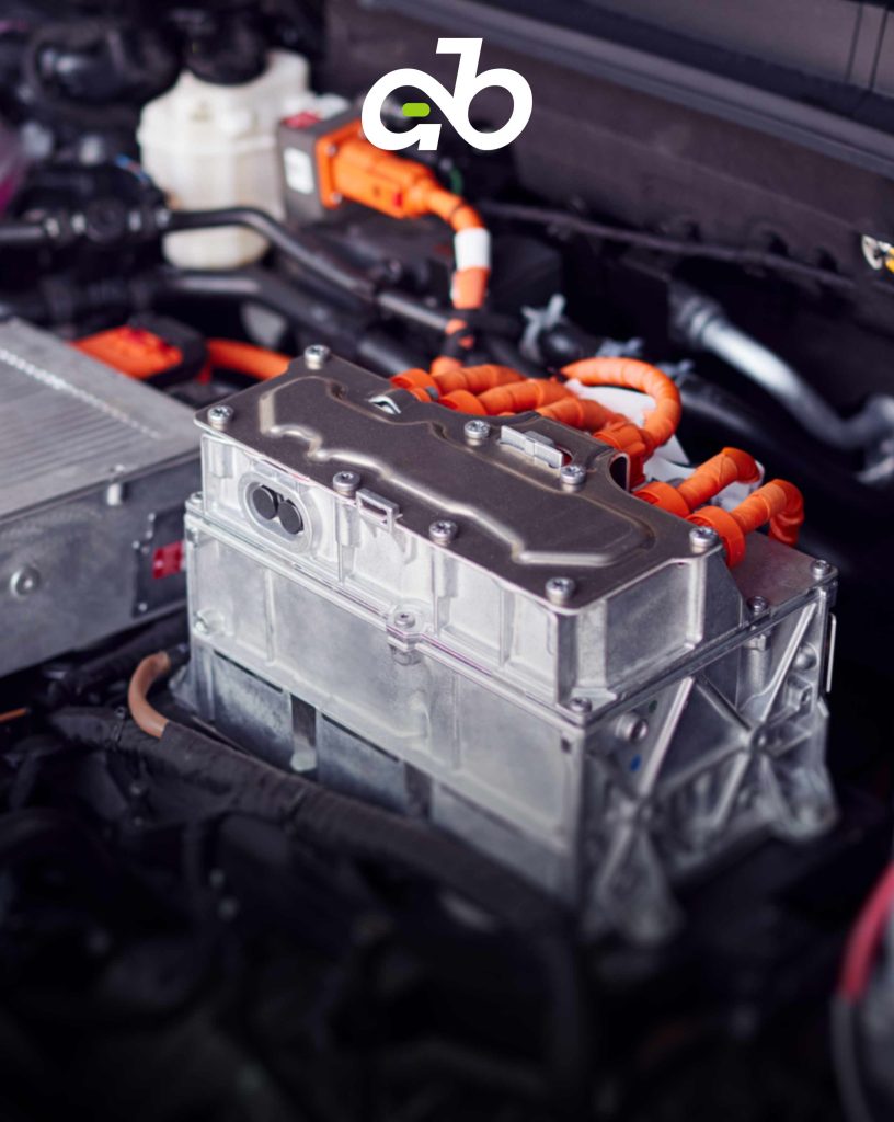 High-voltage power electronics and inverter module installed within an electric vehicle engine bay, featuring heavy-duty orange high-voltage cabling.